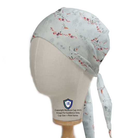 A mannequin head displays the Olaf Frozen Scrub Cap by Medicus Scrub Caps in light blue, featuring floral and bird patterns for added comfort. Designed sustainably with a tied strap at the back, it includes a logo and copyright text at the bottom.