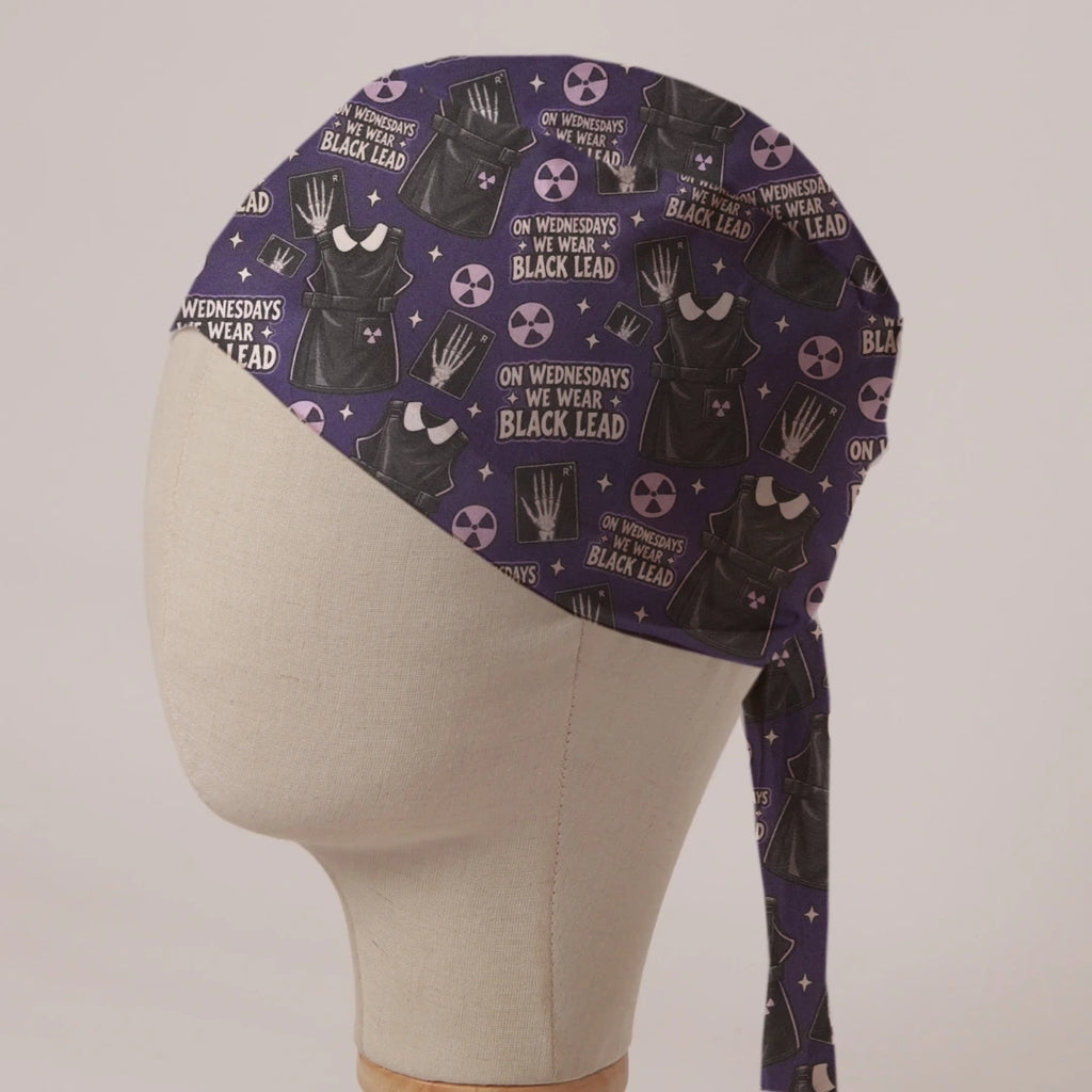 On Wednesdays We Wear Black Lead scrub cap: black lead aprons, hand X-rays and radiation symbols on deep purple