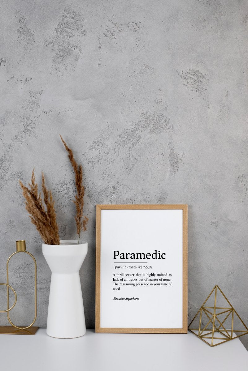 A framed Medicus Scrub Caps Paramedic Definition Poster, available as a digital download in three styles, sits beside modern décor against a textured gray wall.