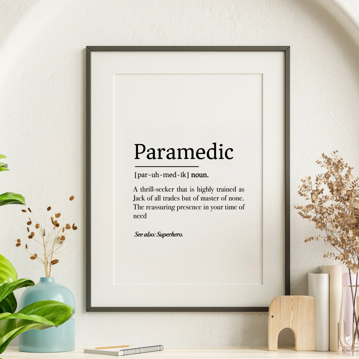 The Paramedic Definition Poster by Medicus Scrub Caps, a digital download in three styles, humorously defines paramedics. Perfect for modern shelf decor with plants.