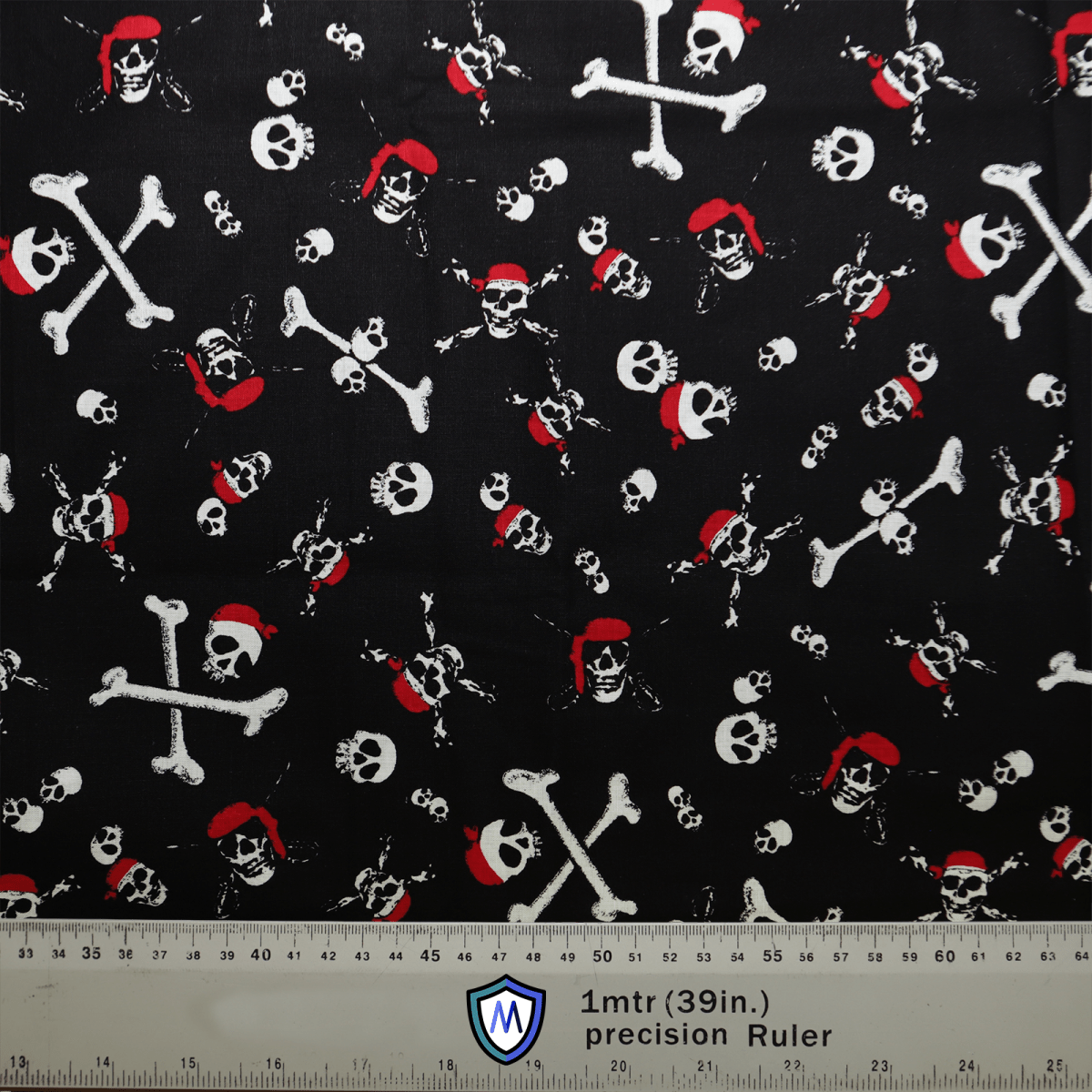 The black fabric features a pirate theme with white skulls and crossbones, some wearing red bandanas. Ideal for crafting a Pirate Skulls and Bones Scrub Cap by Medicus Scrub Caps. A bottom ruler provides measurements in inches and centimeters for precise hat customization.