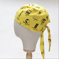 A mannequin head displays a yellow Science Founders Scrub Cap by Medicus Scrub Caps, featuring black graphics and names of iconic scientists such as Hopper and Feynman, tied at the back against a white backdrop.