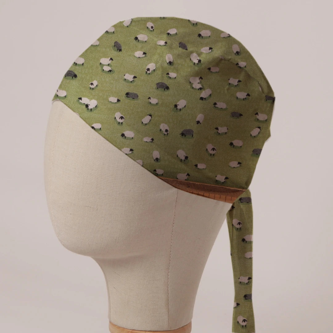 Sheep Fields scrub cap in Bandana tie-back style: black and white sheep on olive green