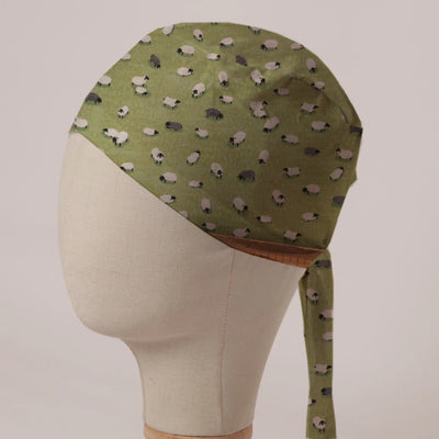 Sheep Fields scrub cap in Bandana tie-back style: black and white sheep on olive green