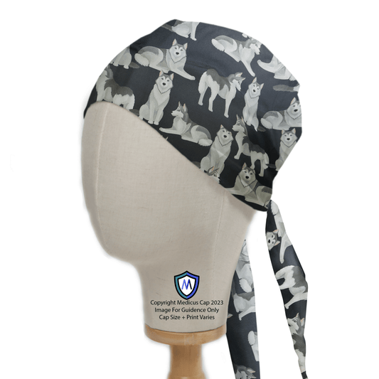 A mannequin head wears the Siberian Husky Dogs Scrub Cap by Medicus Scrub Caps, featuring a gray and black pattern with cartoon Siberian huskies. It ties at the back, and a logo is near the neck of the mannequin.