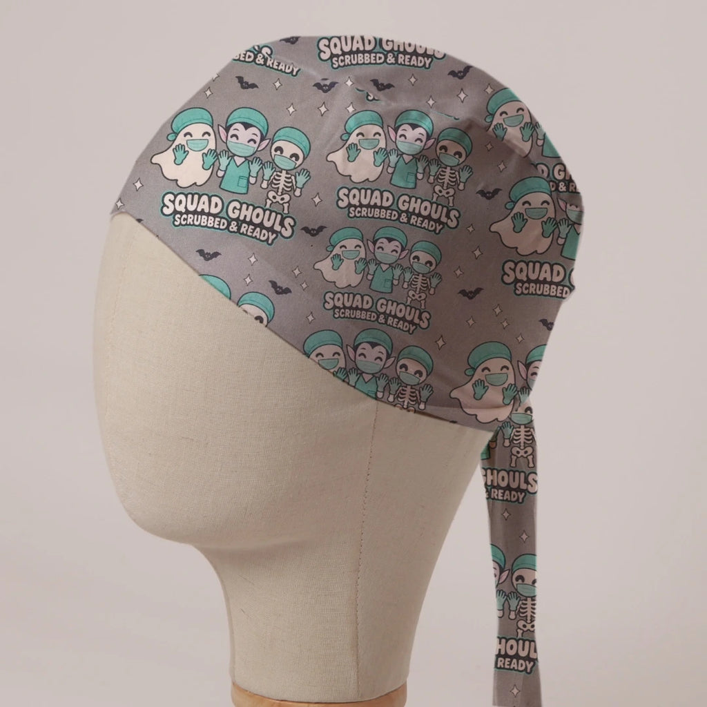 Squad Ghouls Scrubbed & Ready scrub cap: a ghost, vampire and skeleton in teal scrubs with bats on grey