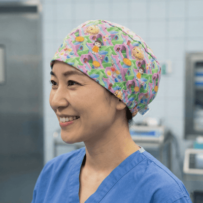 Colourful cartoon animal pattern scrub cap with pink purple green design