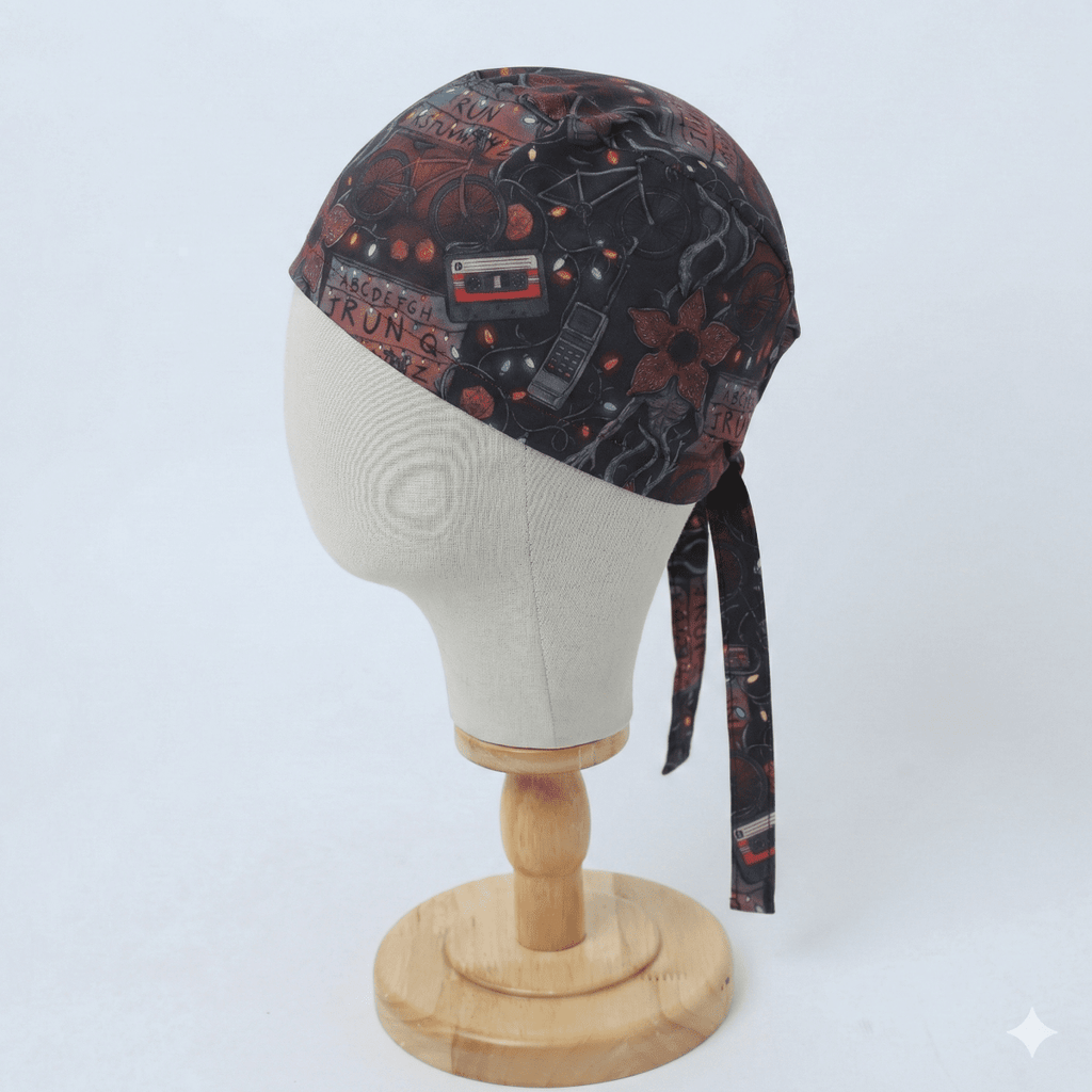 Dark red and black patterned scrub cap with icons displayed on white mannequin head, side profile view