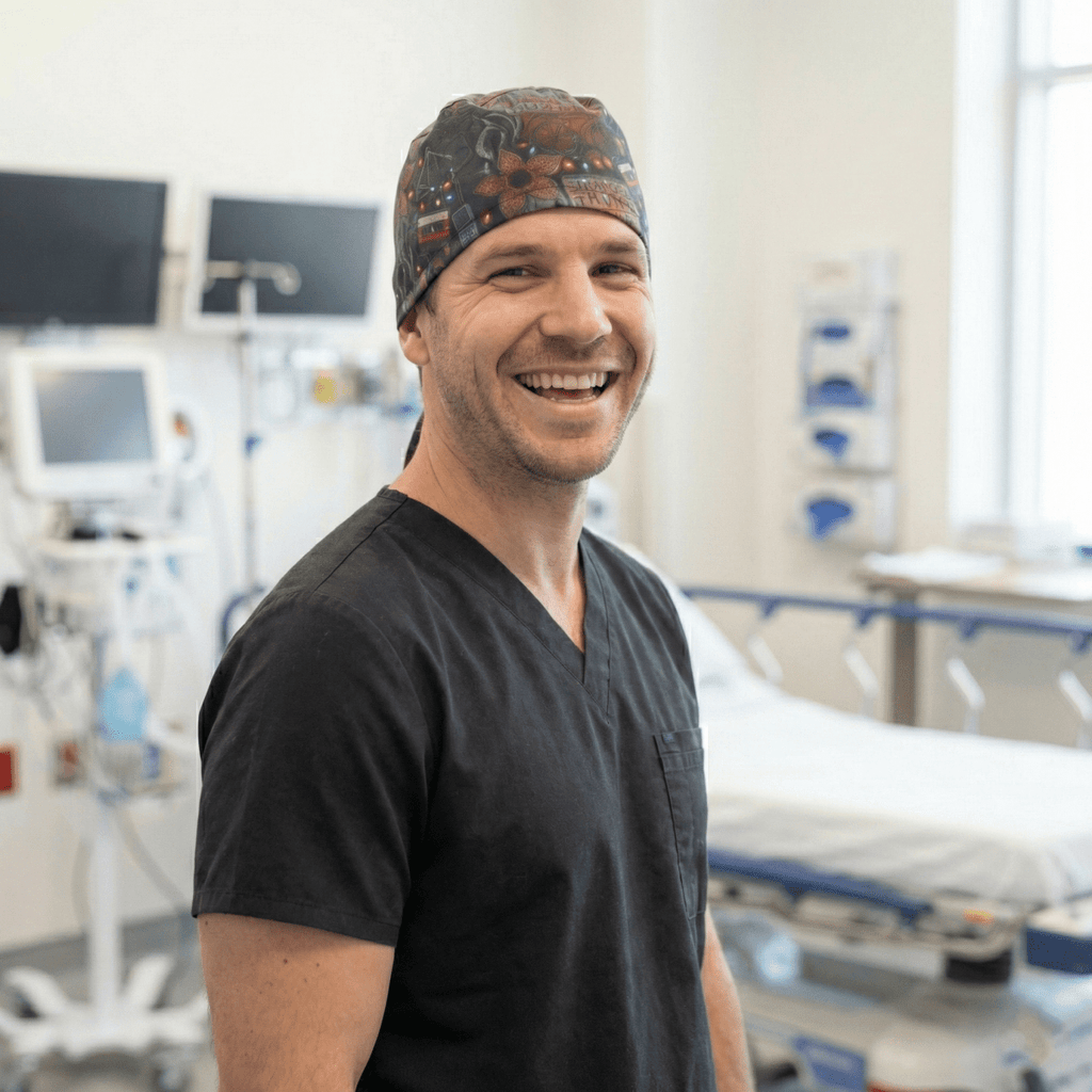 Healthcare professional wearing dark patterned scrub cap with orange and teal icons, smiling in medical setting