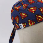 Close-up of Superman logo scrub cap showing red and yellow S symbols on navy fabric with tie detail