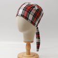 Mannequin head wearing Medicus Scrub Cap with red and white plaid pattern, on a wooden stand against a white backdrop.