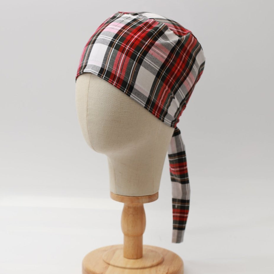 Mannequin head wearing Medicus Scrub Cap with red and white plaid pattern, on a wooden stand against a white backdrop.