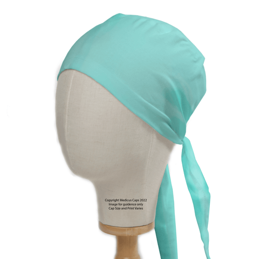 A mannequin head displays a Classic Plain Aqua Green Scrub Cap by Medicus Scrub Caps, featuring a tie-back design for professionalism. This stylish, comfortable, and durable Theatre Hat elegantly covers the head with two loose fabric ends and is supported on a wooden stand.