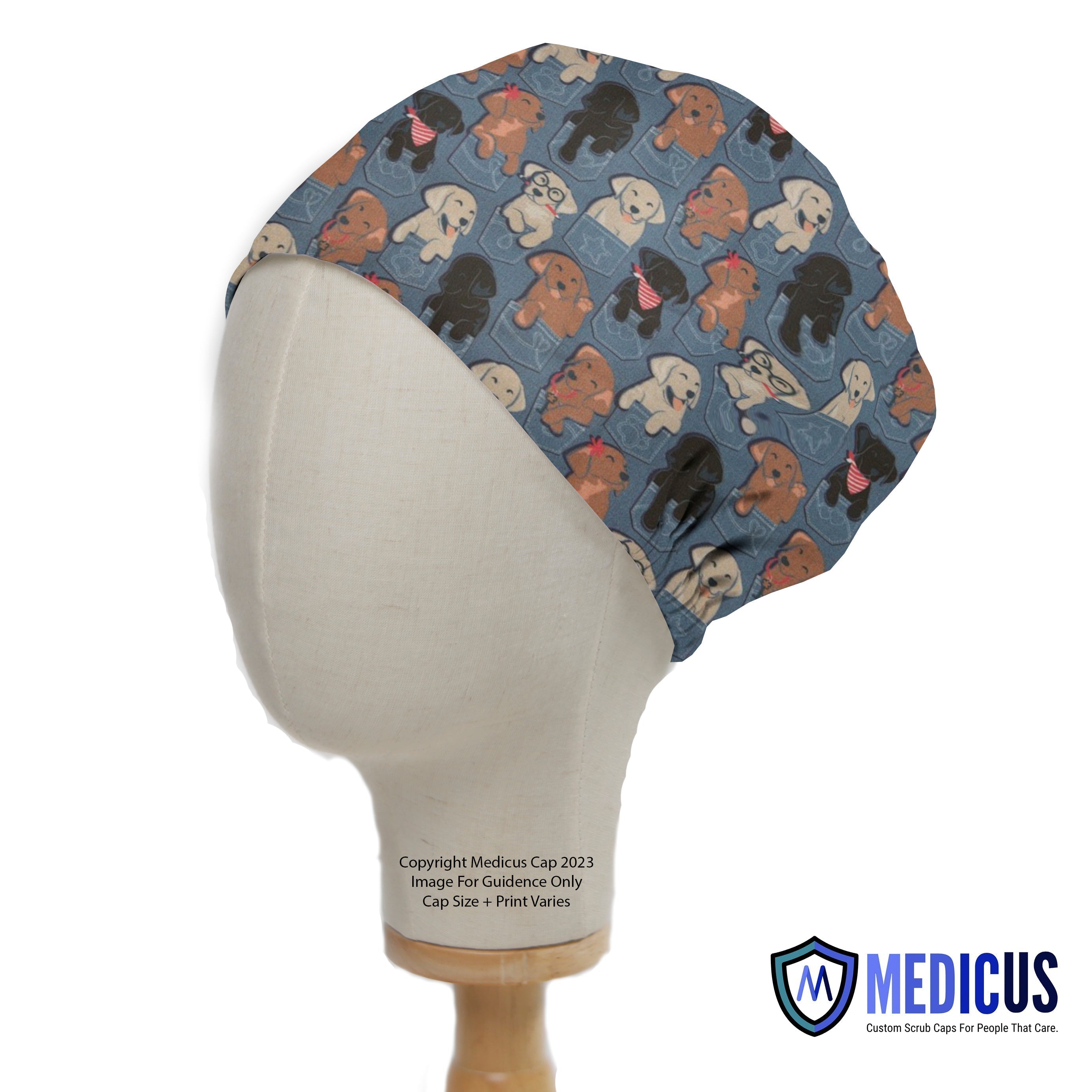 A mannequin head displays a Medicus Scrub Cap featuring playful dogs peeking from jean pockets on a blue background, reflecting their custom, fun designs.