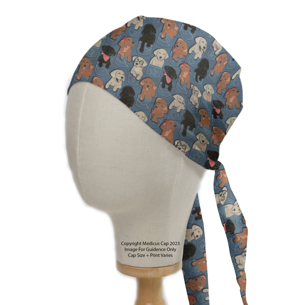 A mannequin head displays a Medicus Scrub Cap featuring playful dogs in jean pockets. The "Dogs In Jean Pockets Scrub Cap" includes two long ties at the back.