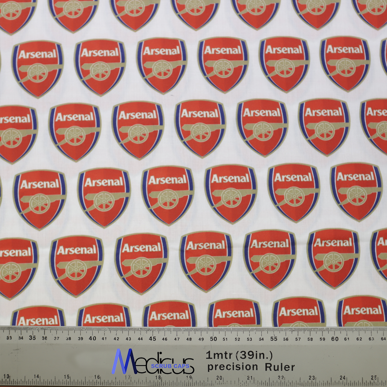 The Arsenal Scrub Cap by Medicus Scrub Caps features red and white fabric with repeating Arsenal logos and a precision ruler for accurate crafting.