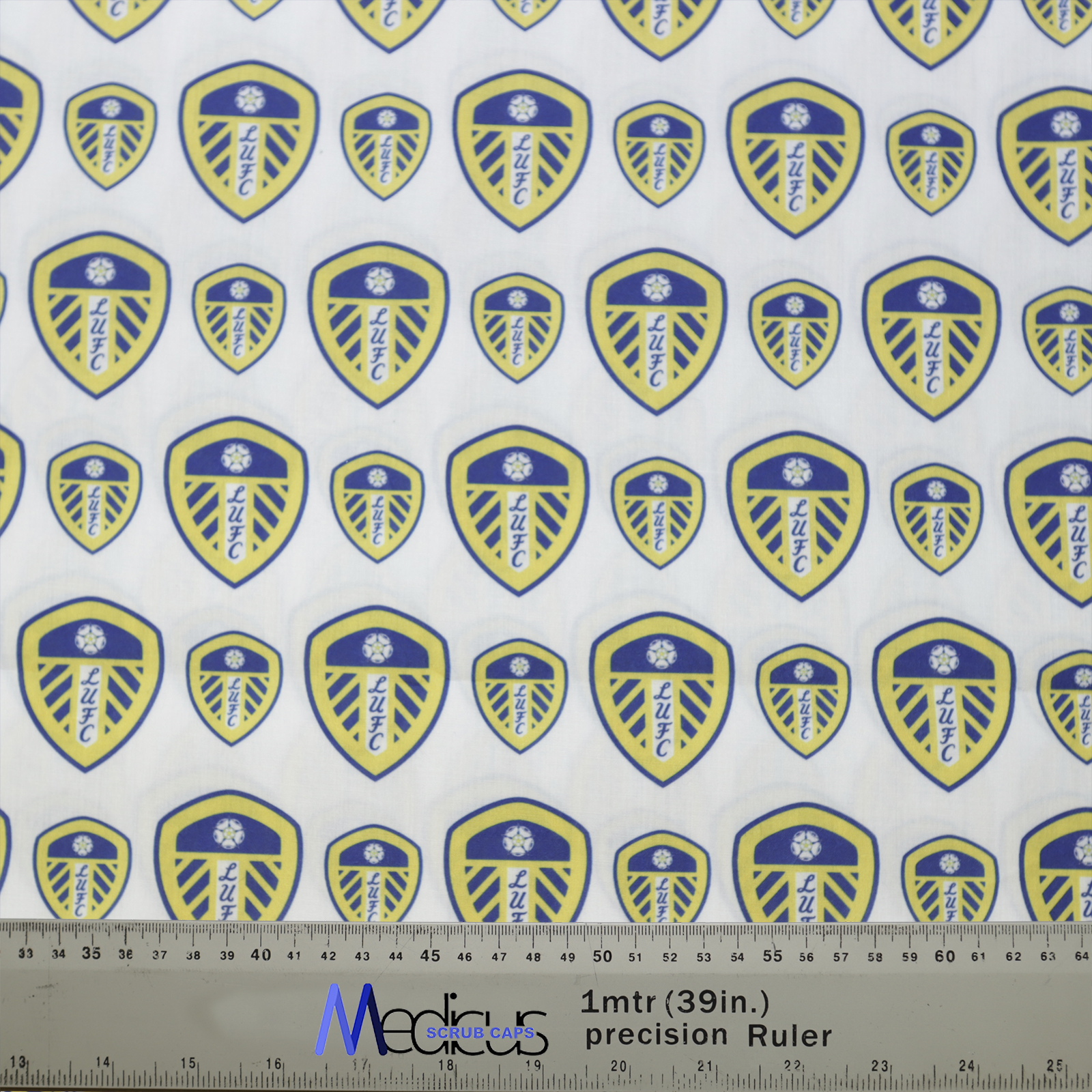 Patterned fabric with blue and yellow Leeds United emblems, perfect for a football-themed Medicus Scrub Cap. Includes Medical Precision Ruler for scale.