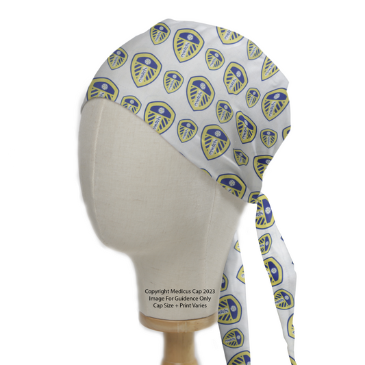 The Football Club Leeds United Scrub Cap by Medicus Scrub Caps features a blue and yellow club shield pattern on white, eco-friendly with long ties for medical professionals.