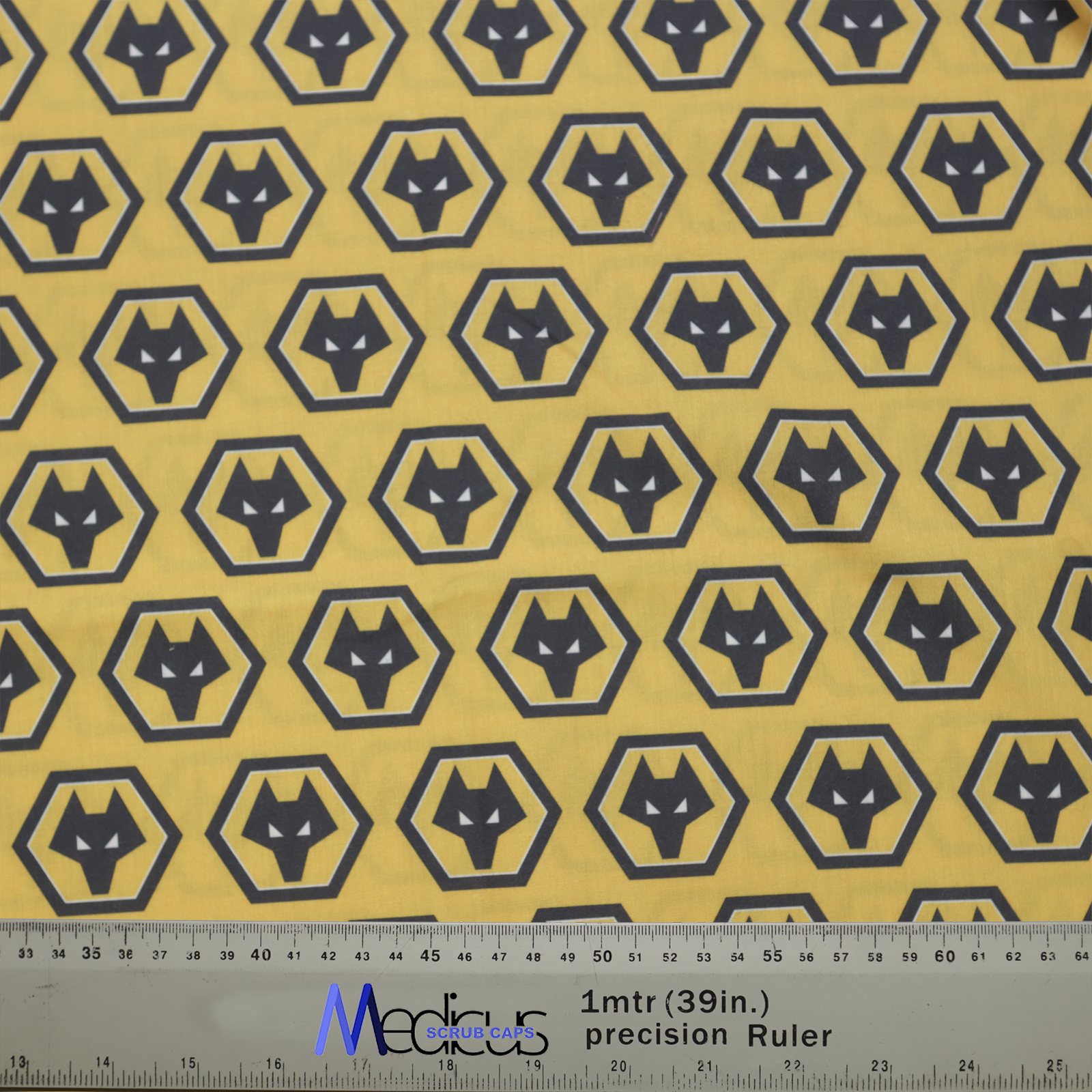 Yellow fabric with black hexagonal wolf head patterns, measured with a ruler. Perfect for custom Medicus Scrub Caps, inspired by Football Club Wolverhampton.