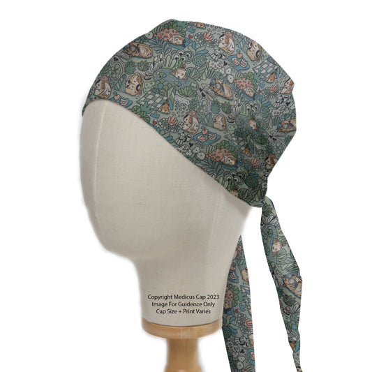 A mannequin head wears a Medicus Scrub Caps Guinea Pig Wildlife Scrub Cap, featuring a playful guinea pig and foliage pattern on a green base, tied at the back.