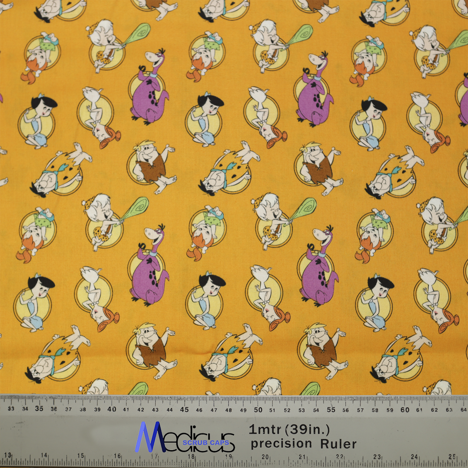 An orange Medicus Scrub Cap features Flintstones characters, cavemen, and dinosaurs, with a ruler ensuring precise fit for this fun, nostalgic design.