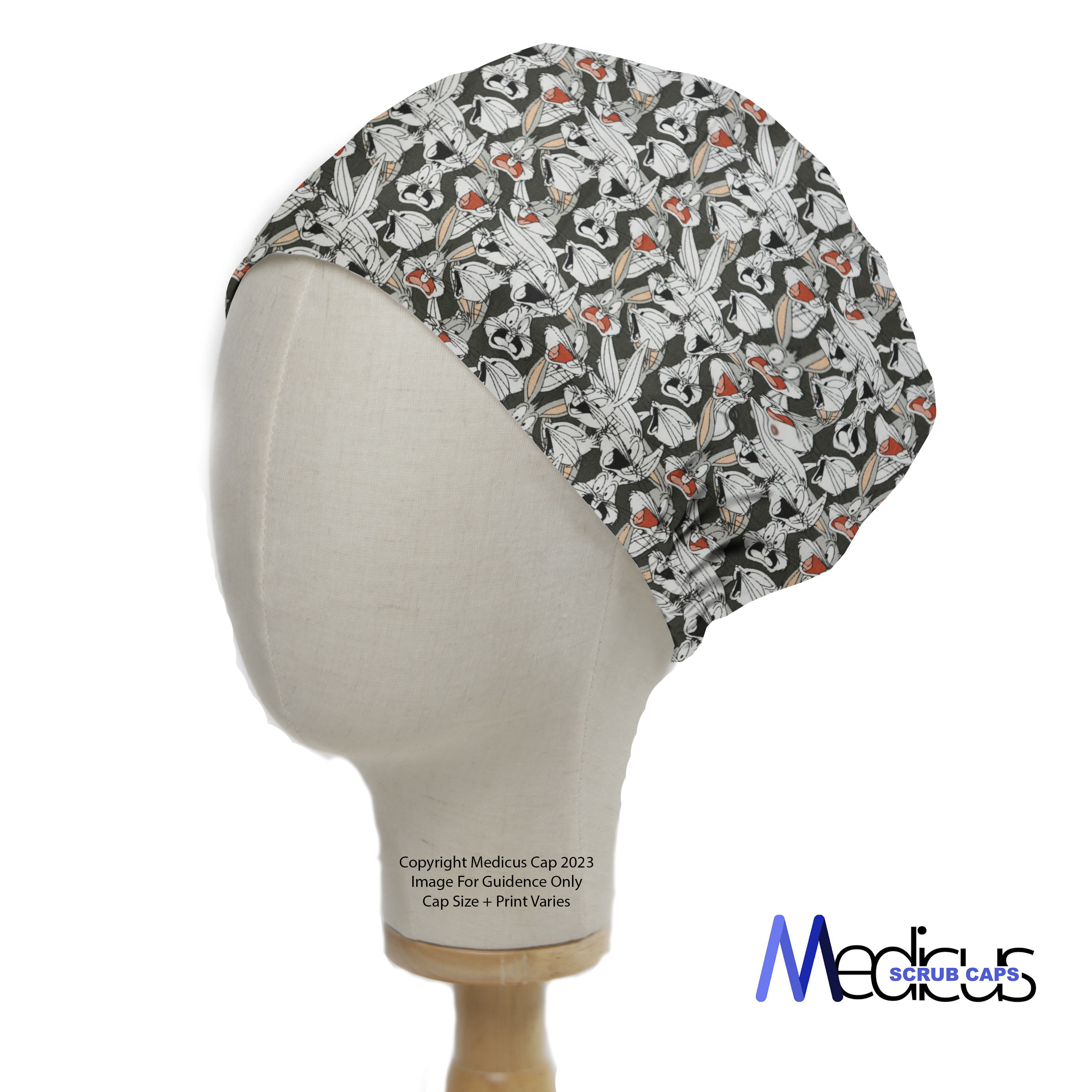 A mannequin head displays the Medicus Scrub Caps TV Cartoon Looney Tunes Bugs Bunny Scrub Cap, featuring a playful pattern with characters and red accents on a dark background.