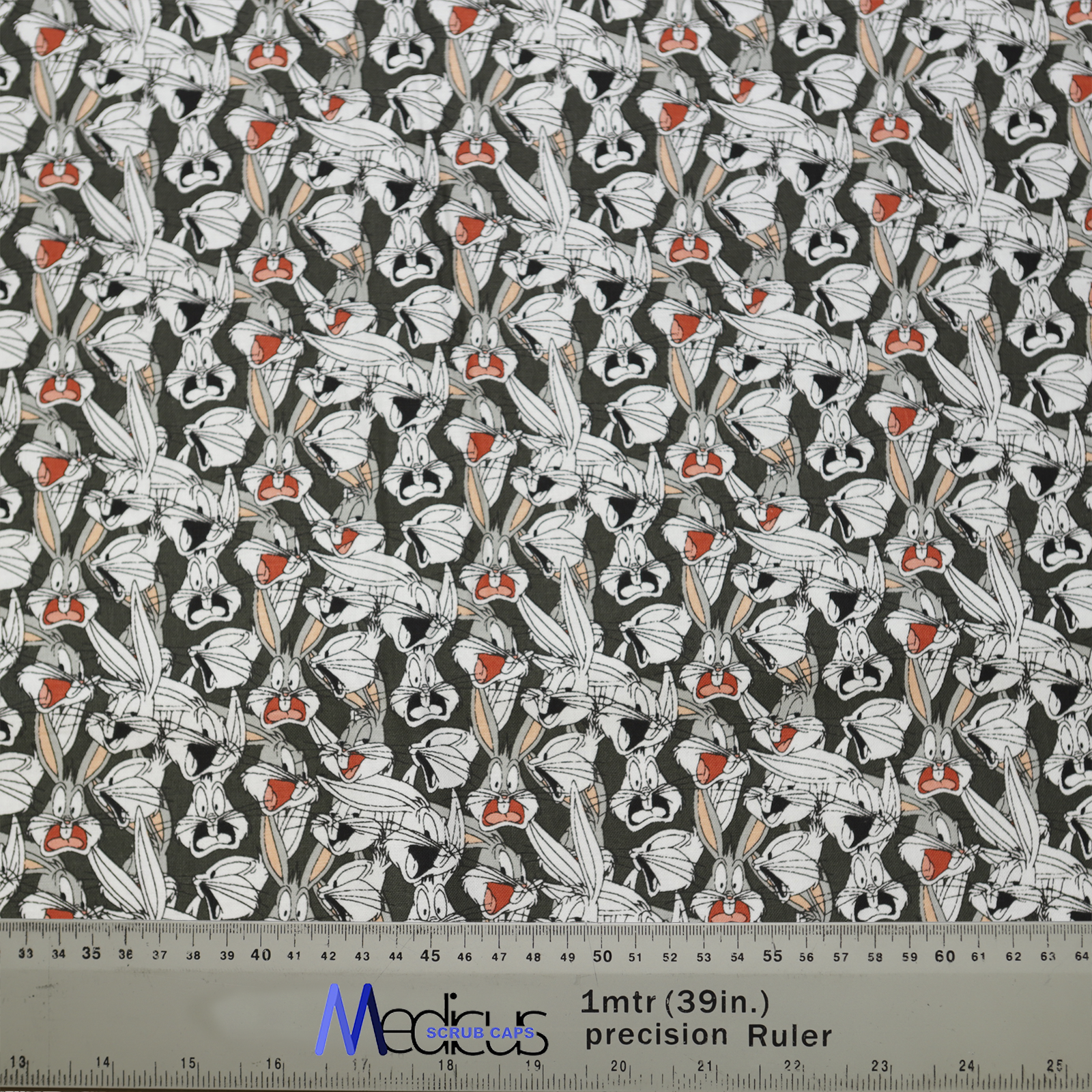 The Medicus Scrub Caps TV Cartoon Looney Tunes Bugs Bunny Scrub Cap features expressive Bugs Bunny faces on a dark gray background, with a ruler for scale.
