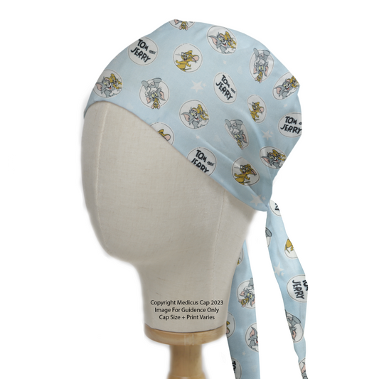 The Medicus Scrub Caps Tom And Jerry Circles On Blue Scrub Cap features playful cartoon prints on a light blue fabric, styled on a mannequin head.