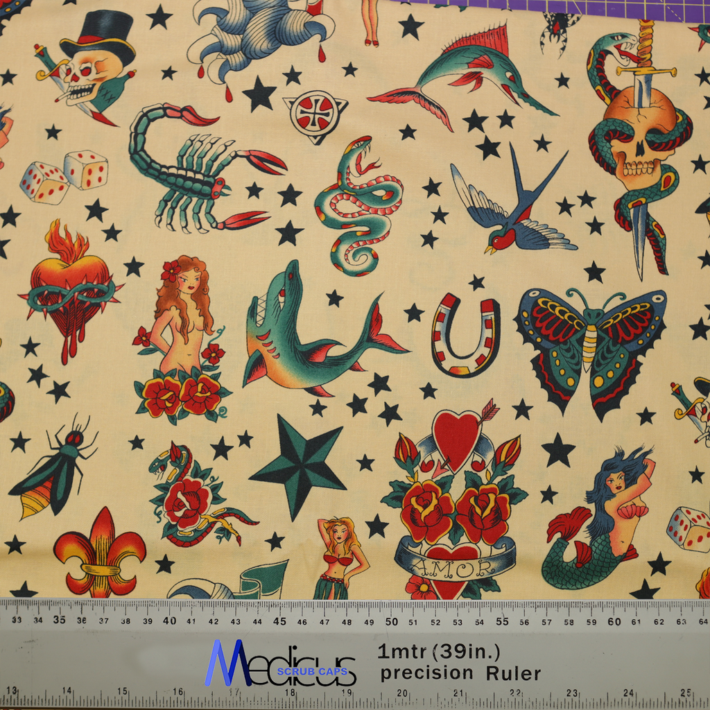 The Tattoos #3 Sea Pirates Scrub Cap by Medicus Scrub Caps features a bold tattoo-inspired design with sharks, mermaids, skulls, and roses. Includes a ruler for scale.