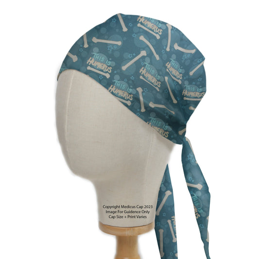 A mannequin wears the This Is Humerus Bones Scrub Cap by Medicus Scrub Caps, featuring a playful bone pattern and tied straps.