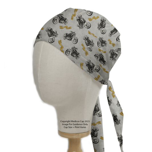 A mannequin head showcases the Medicus Scrub Caps Bike Biker For Life scrub cap with motorcycle prints and yellow swirls on light gray. Designed for medical comfort, it features ties and text near the base.