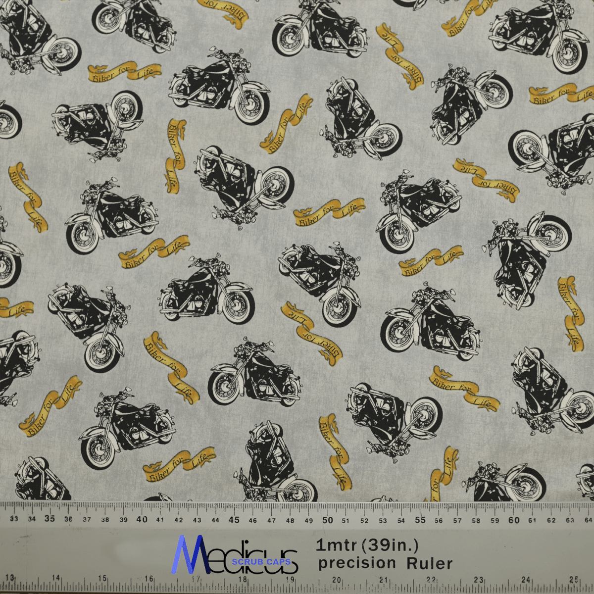 Black motorcycles and yellow ribbons with text adorn this gray Bike Biker For Life Scrub Cap by Medicus Scrub Caps, perfect for crafting a medical comfort cap. The fabric includes precise measurements for accuracy, displayed in inches and centimeters with a clear ruler on the bottom.