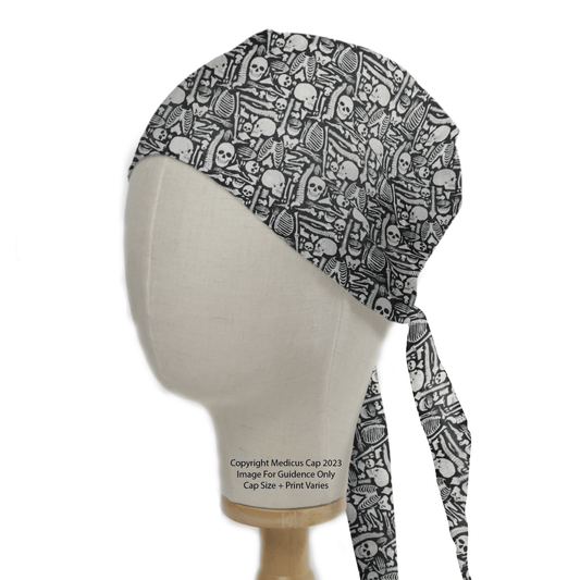 A mannequin head displays the eco-friendly Bones Cartoon Anatomy Scrub Cap by Medicus Scrub Caps, featuring a skull pattern in black and white. It combines medical fashion with personality, complete with extended fabric ties draping gracefully down the side.