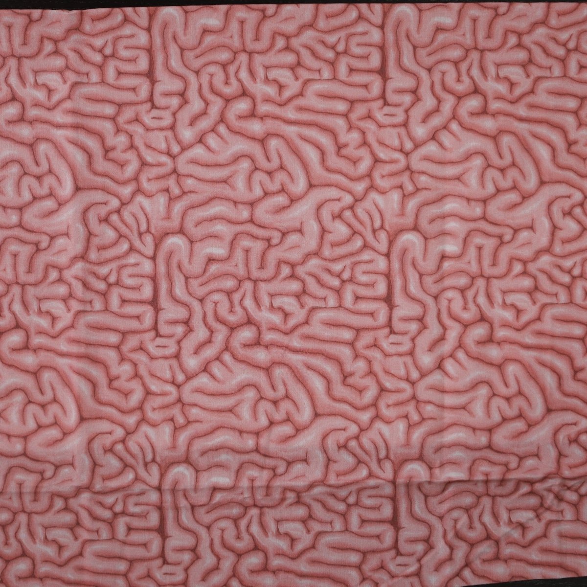 A close-up image highlights the intricate pink pattern of Medicus Scrub Caps Brains Pink Human Scrub Caps, resembling brain coral or a stylized brain surface, with raised ridges and valleys against a muted background, symbolizing detailed sustainability.