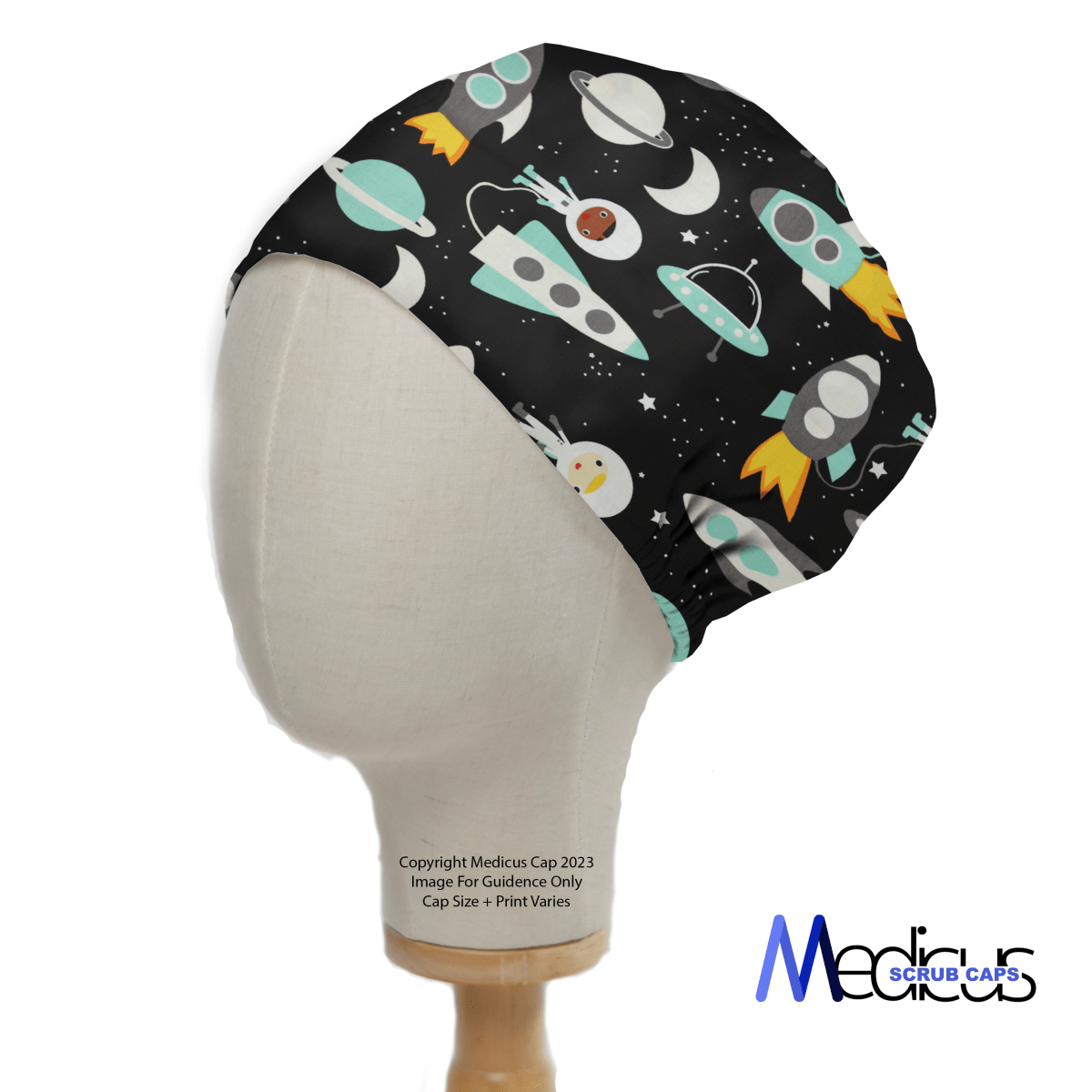 Medicus Scrub Caps presents the Cartoon Spaceships Blue Scrub Cap, modeled by a mannequin head and featuring playful spaceships, planets, and stars on a black background. This eco-friendly healthcare accessory blends style with practicality. Copyright and model details are below.