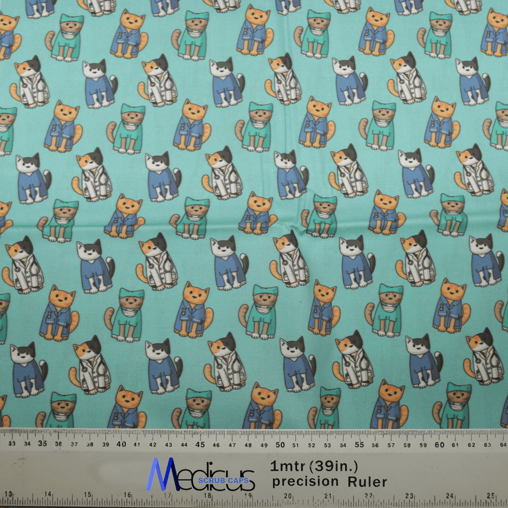 The Cat Doctor Surgeons Scrub Cap by Medicus Scrub Caps showcases cartoon cats dressed as doctors in medical scrubs and lab coats on a teal background, ideal for a personalized touch. A ruler at the bottom indicates fabric scale.