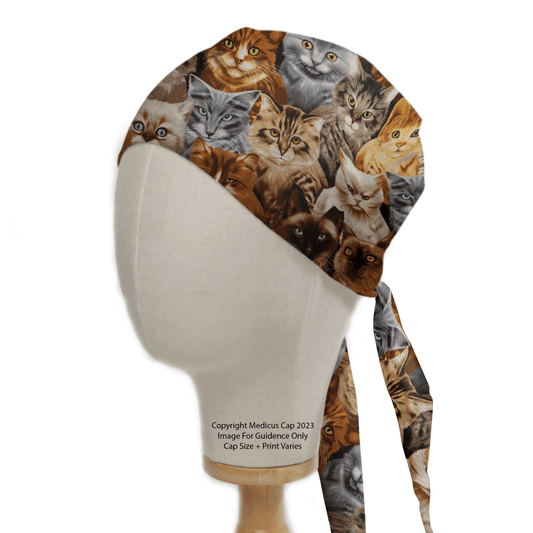 A mannequin head showcases the Cat Starring Scrub Cap by Medicus Scrub Caps, featuring a vibrant design with diverse cat faces in various colors and breeds for an eco-friendly, whimsical touch to your attire.