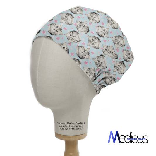 The Cat Stars Scrub Cap by Medicus Scrub Caps features cats with glasses and pink stars on a light blue background. Eco-friendly and reusable, it is displayed on a mannequin head with the Medicus Scrub Caps logo in the bottom right corner.