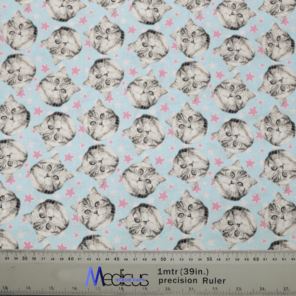 Discover Medicus Scrub Caps new Cat Stars design, boasting cute cat faces with large eyes on a light blue background with pink stars. This eco-friendly, reusable scrub cap includes a ruler for scale and adds a playful flair to your work attire.