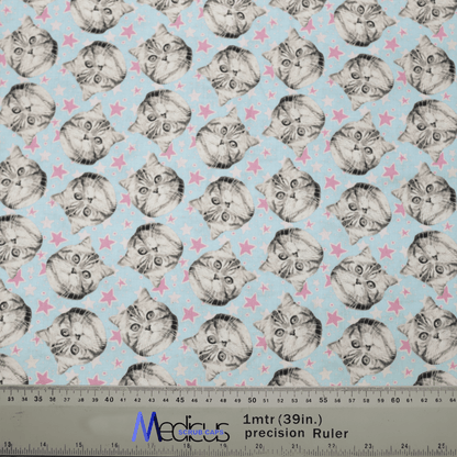 Discover Medicus Scrub Caps new Cat Stars design, boasting cute cat faces with large eyes on a light blue background with pink stars. This eco-friendly, reusable scrub cap includes a ruler for scale and adds a playful flair to your work attire.