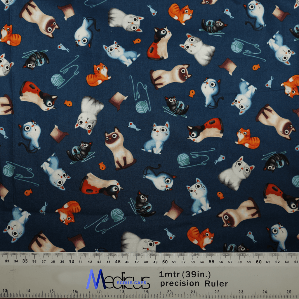The Cats Love Yarn Scrub Cap by Medicus Scrub Caps features a playful pattern of cartoon cats in orange, blue, and white, with yarn balls, mice, fishbones, and fishbowls. Made from hypoallergenic cotton. It includes a precision ruler labeled Med Sigura CATS for NHS-compliant measurements.