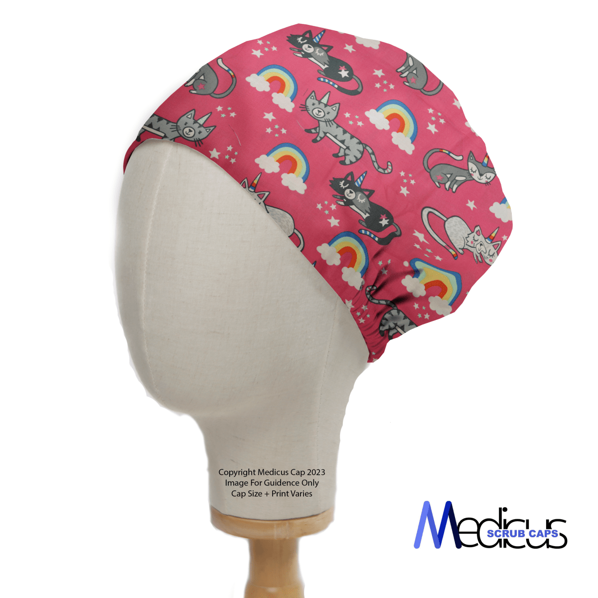 Against a pink backdrop featuring cartoon cats, rainbows, and stars, a mannequin head sports the Cats Unicorn Rainbow Pink Scrub Cap by Medicus Scrub Caps, celebrated for its sustainability, comfort, and breathability.