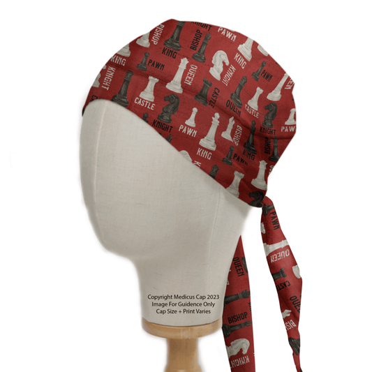 The mannequin head displays a red Chess Queens Gambit Scrub Cap by Medicus Scrub Caps, inspired by the Queens Gambit, featuring chess piece names like King, Queen, and Knight. Stylish ties hang down the back for a perfect fit.