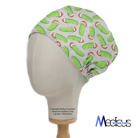 A mannequin head displays a Medicus Scrub Cap with a playful Christmas Pickle Rick design. The cap features characters wearing Santa hats on a light gray background, ideal for medical professionals. The Medicus logo is visible in the bottom right corner.