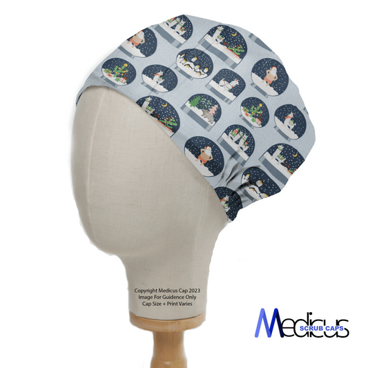 A mannequin displays the Christmas Snow Globes Blue Scrub Cap by Medicus Scrub Caps, featuring whimsical snowmen and trees in Christmas globes. It has a contrasting white band at the bottom and an elegant logo on the lower right.