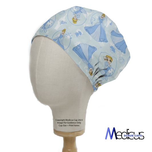 The Cinderella Scrub Cap by Medicus Scrub Caps, displayed on a mannequin, features light blue fabric with cartoon princess designs in various royal poses. Designed for healthcare professionals, it showcases the Medicus Scrub Caps logo on the bottom right.