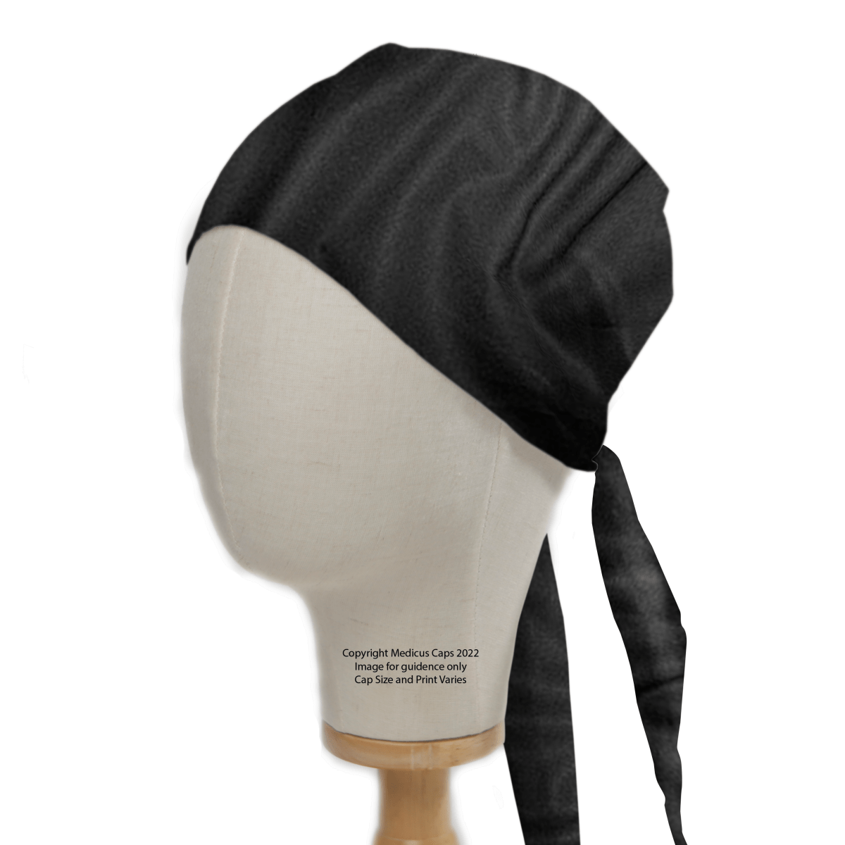 A Classic Plain Black Scrub Cap by Medicus Scrub Caps is showcased on a mannequin head, featuring a smooth texture and back ties with two long straps. Perched on a wooden base, this essential accessory for medical professionals has visible text enhancing its practical appeal.