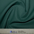 A piece of bottle green fabric is gracefully draped, with a ruler in inches and centimeters at the bottom, highlighting the quality-assured width—perfect for crafting an eco-friendly Classic Plain Bottle Green Scrub Cap from Medicus Scrub Caps.