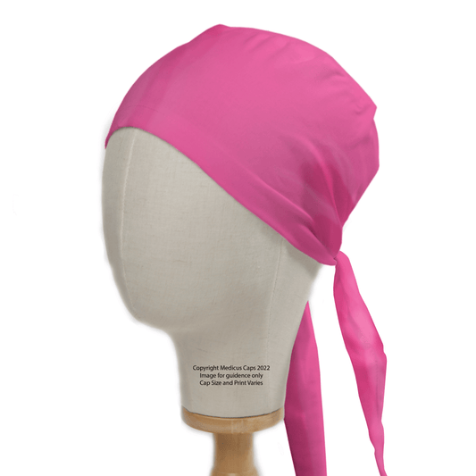 Medicus Scrub Caps presents the Classic Plain Bright Pink Scrub Cap, elegantly displayed on a mannequin head. Tied at the back with long fabric ends, it sits on a wooden stand, perfect for medical professionals seeking style and practicality without any visible pattern or logo.