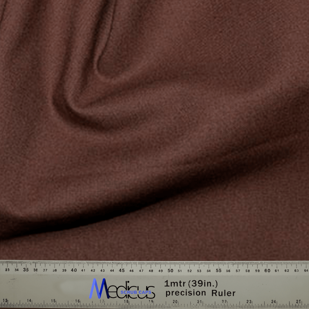 A close-up of soft, sustainable brown fabric draped in folds, paired with a precision ruler showing measurements in cm and inches—perfect for crafting the Classic Plain Brunette Brown Scrub Cap by Medicus Scrub Caps for medical professionals.